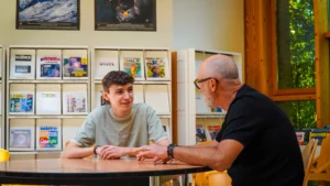 Sheldon et Georges, duo de mentorat entrain de discuter dans le CDI du lycée