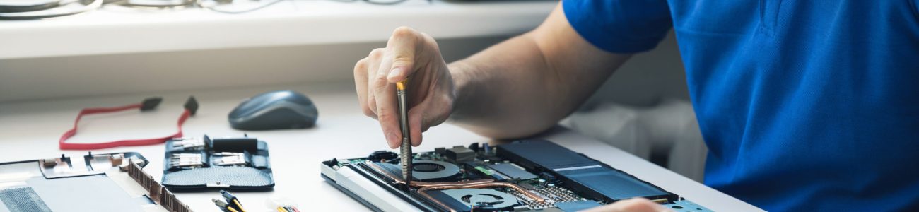 computer repair service - technician repairing broken laptop in office